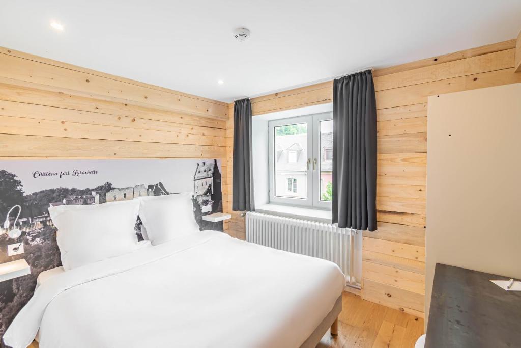 a bedroom with a white bed and a window at Esplanade Hotel in Diekirch