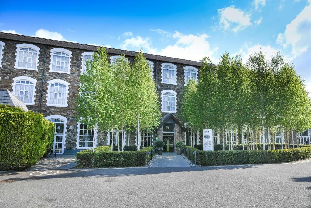 a large brick building with trees in front of it at Blarney Woollen Mills Hotel - BW Signature Collection in Blarney