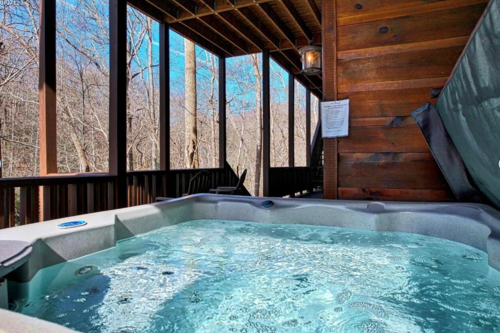 a jacuzzi tub in a cabin with windows at Vintage Luxury Mountain Cabin, Creekside, King Bed, Spa, Fire Pit, Game Room, DogsOk in Hiawassee