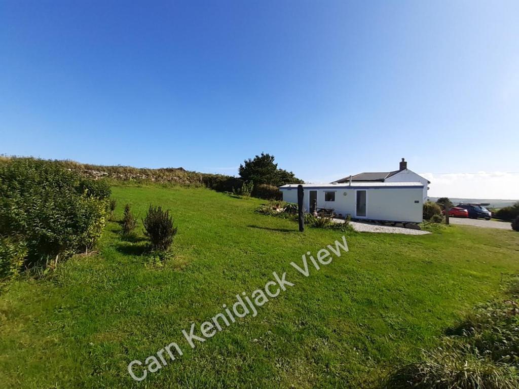 a house on the side of a grassy hill at Carn Kenidjack View Caravan, space, peace and tranquillity in Penzance