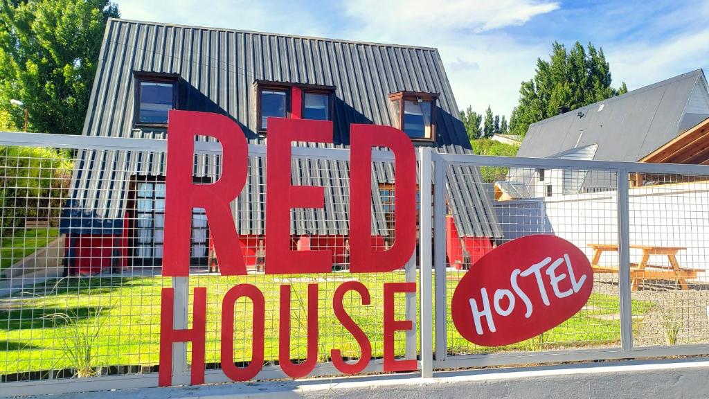 een rood bord op een hek voor een huis bij Red House Hostel in El Calafate