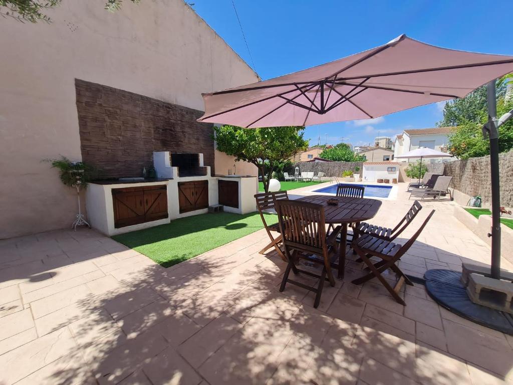 a patio with a table and chairs and an umbrella at Casa con piscina privada Cesar - MarCalma in Creixell