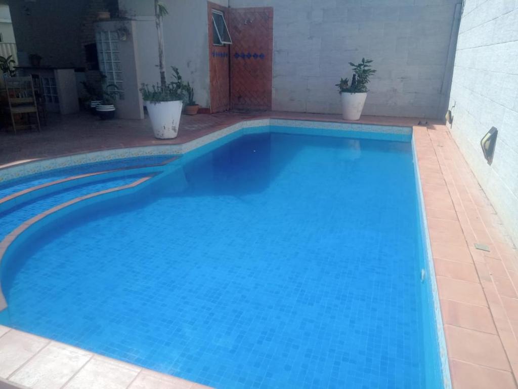 a large blue swimming pool with two potted plants at Hostel e Pousada do Bosque in Rio Branco