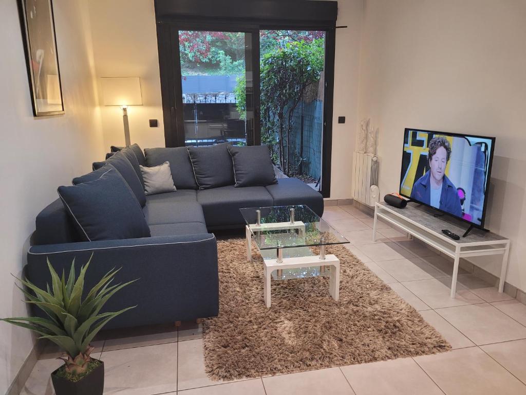 uma sala de estar com um sofá azul e uma televisão em APPARTEMENT standing 2 pieces avec jardin entre Paris & Dysney em Bry-sur-Marne