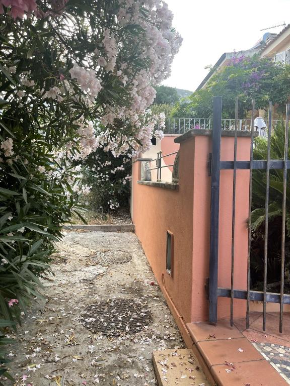 una recinzione di fronte a una casa con fiori rosa di Appartamento La Guglia a Cala Gonone