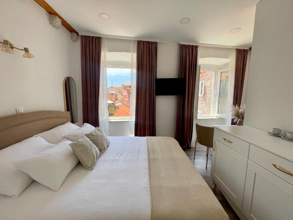 a bedroom with a large white bed and a desk at Ida Old Town Rooms in Dubrovnik