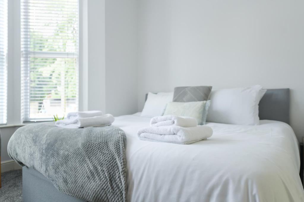 a bedroom with a white bed with towels on it at The Linden Grove Apartments in Nottingham