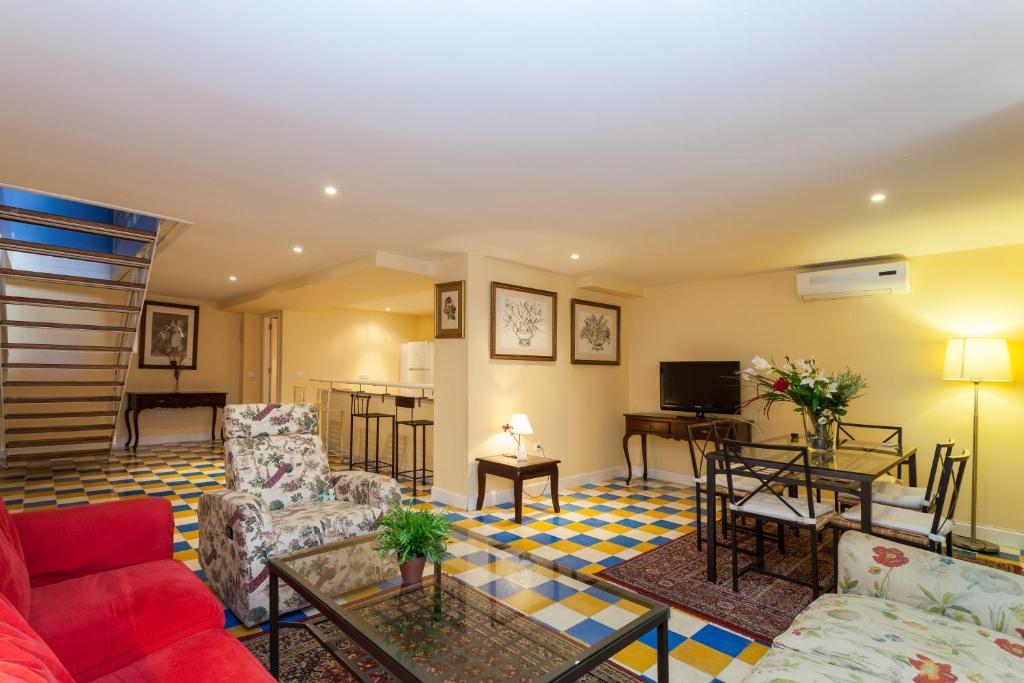 een woonkamer met een bank en stoelen en een tv bij Las Casas de Moratin in Sevilla