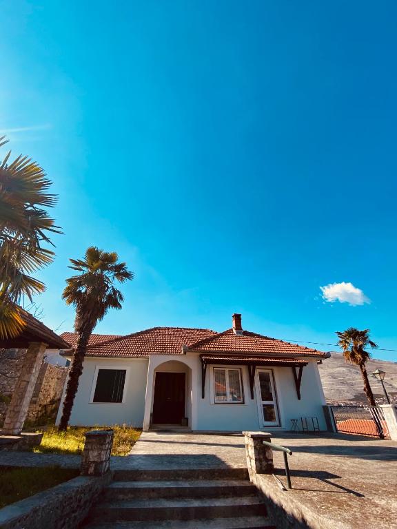a white house with palm trees in front of it at Vila Zorka in Trebinje