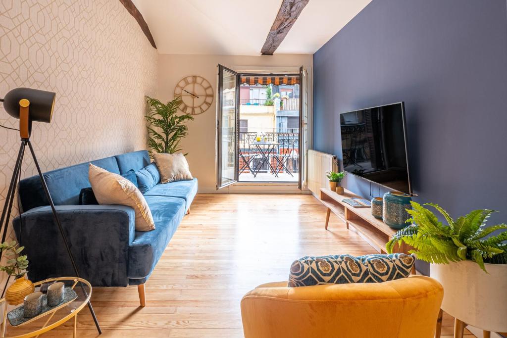 ein Wohnzimmer mit einem blauen Sofa und einem TV in der Unterkunft Patagonia Downtown & Beach by DLA in San Sebastián