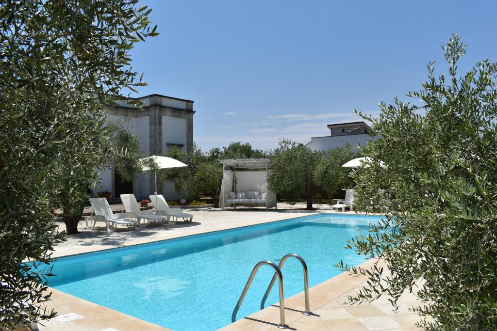 a swimming pool with chairs and a building at B&B Li Ccoti in Cannole