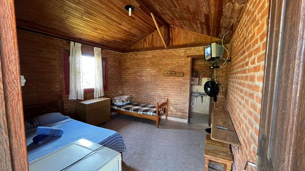 a bedroom with a bed and a brick wall at Chalés Ouro de Minas in Conceição da Ibitipoca