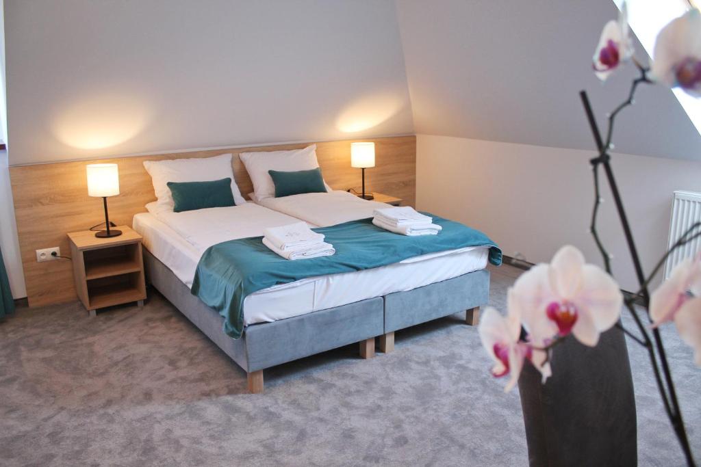 ein Schlafzimmer mit einem Bett, zwei Lampen und Blumen in der Unterkunft Perła Dunajca Zakliczyn in Zakliczyn