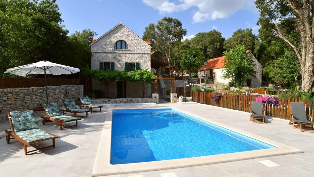 einen Pool mit Stühlen und ein Haus in der Unterkunft Traditional villa Juta for 8 people in Hrvace