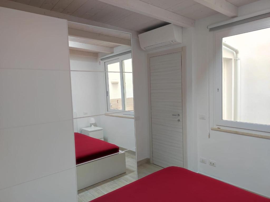 Habitación blanca con cama roja y ventana en Apartments Villas Cagliari, en Cagliari