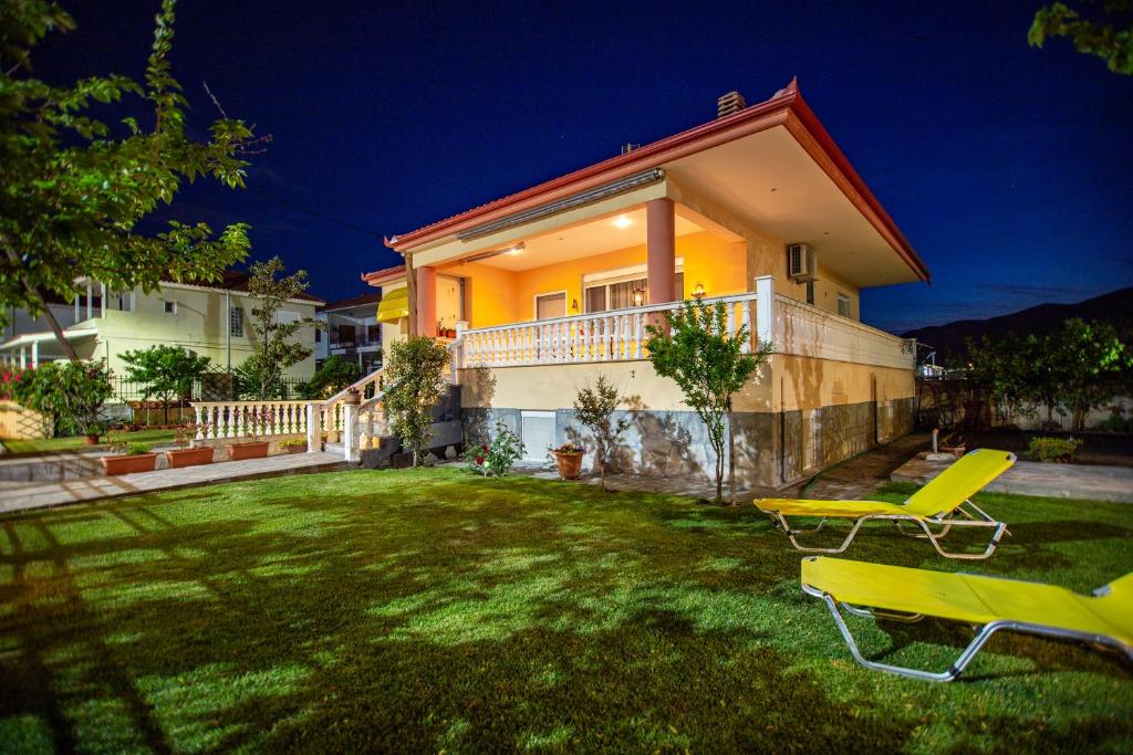 a house with a yard with two lawn chairs at Kaliva House in Nea Vrasna