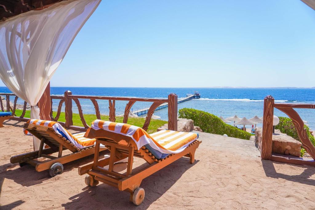 two lounge chairs on a beach with the ocean at Charmillion Club Resort in Sharm El Sheikh