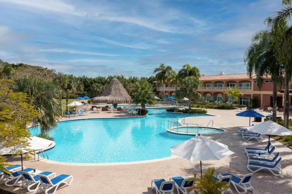 een zwembad in een resort met stoelen en parasols bij Hodelpa Garden Suites - All Inclusive in Juan Dolio