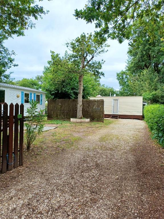 une allée avec une clôture et un arbre dans l'établissement Charmant Bungalow à Saint-Pierre-d'Oléron avec Jardin, à Saint-Pierre-dʼOléron