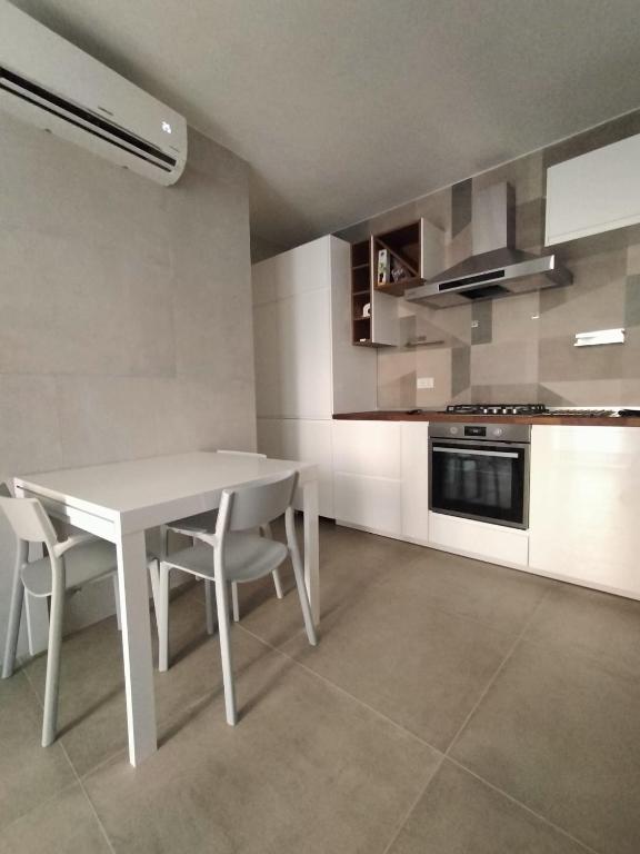 a white kitchen with a white table and chairs at Giù da Nonna in Gaeta