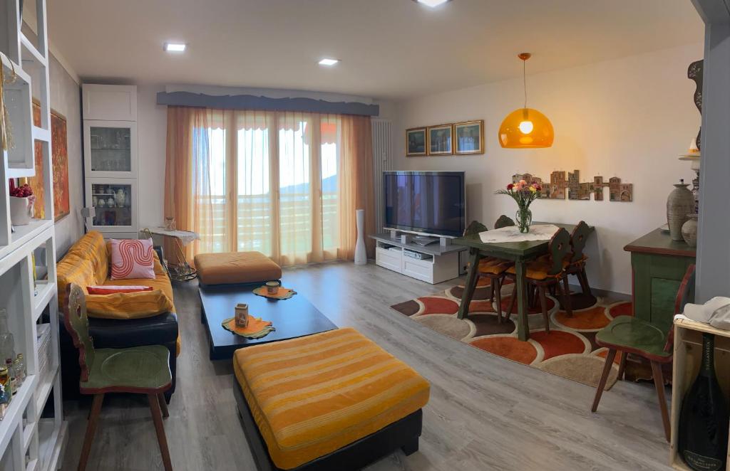 een woonkamer met een bank, een tafel en een tv bij Moderno appartamento con splendida vista Alpi in Crans-Montana