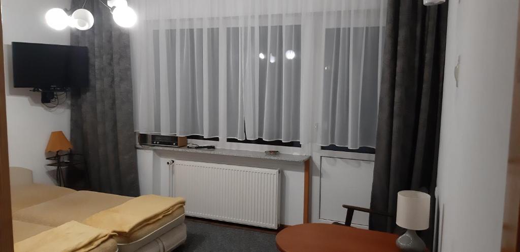 a hotel room with a bed and a tv and curtains at Międzyzdroje ul Nowomyśliwska 60 in Międzyzdroje