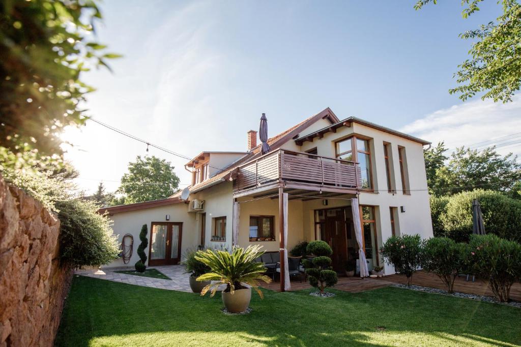 a house with a balcony and a yard at Csendeskert Wellness Apartments - Garden, grill, chill in Balatonalm&aacute;di