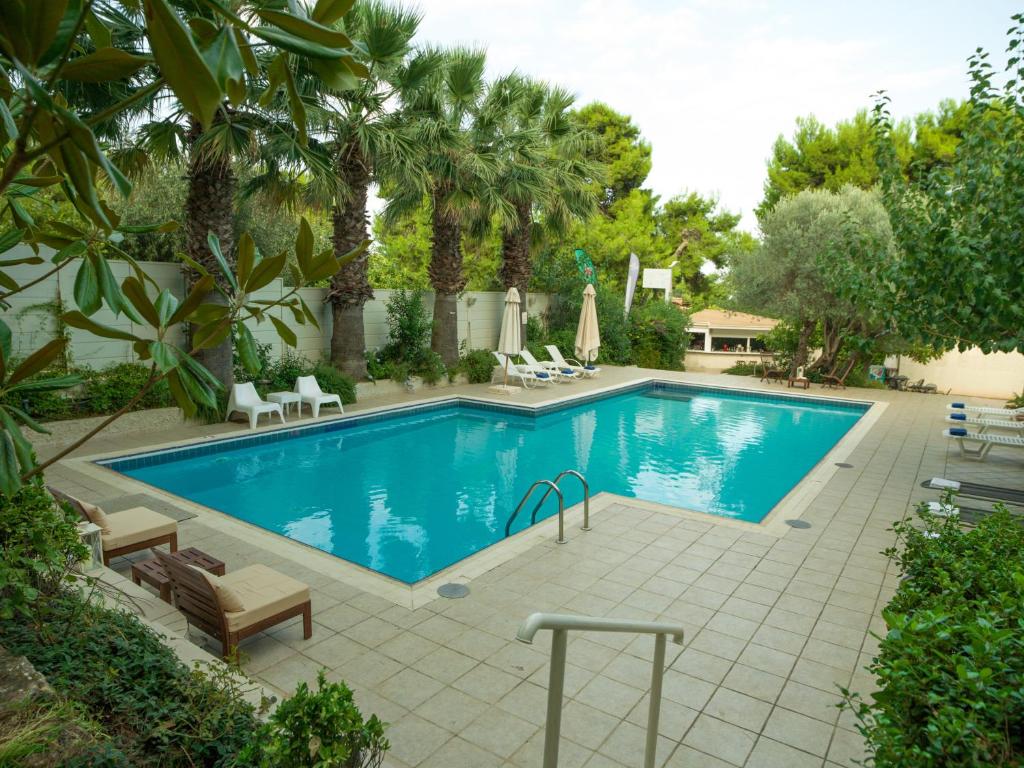 a swimming pool in a yard with palm trees at Myrto Hotel in Mati