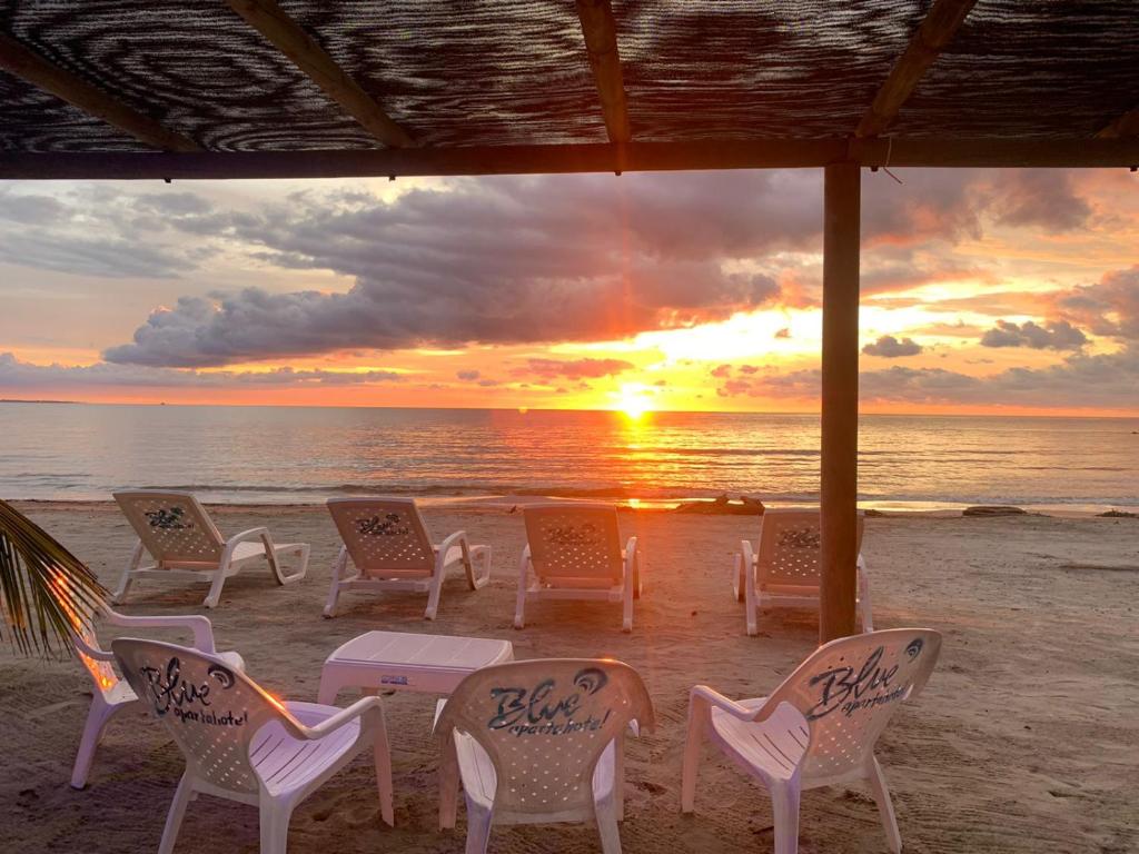 eine Gruppe von Stühlen und Tischen am Strand mit Sonnenuntergang in der Unterkunft Blue Apartahotel in Coveñas