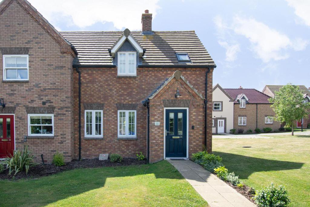 a brick house with a red door in a yard at Lilipad Cottage in Reighton