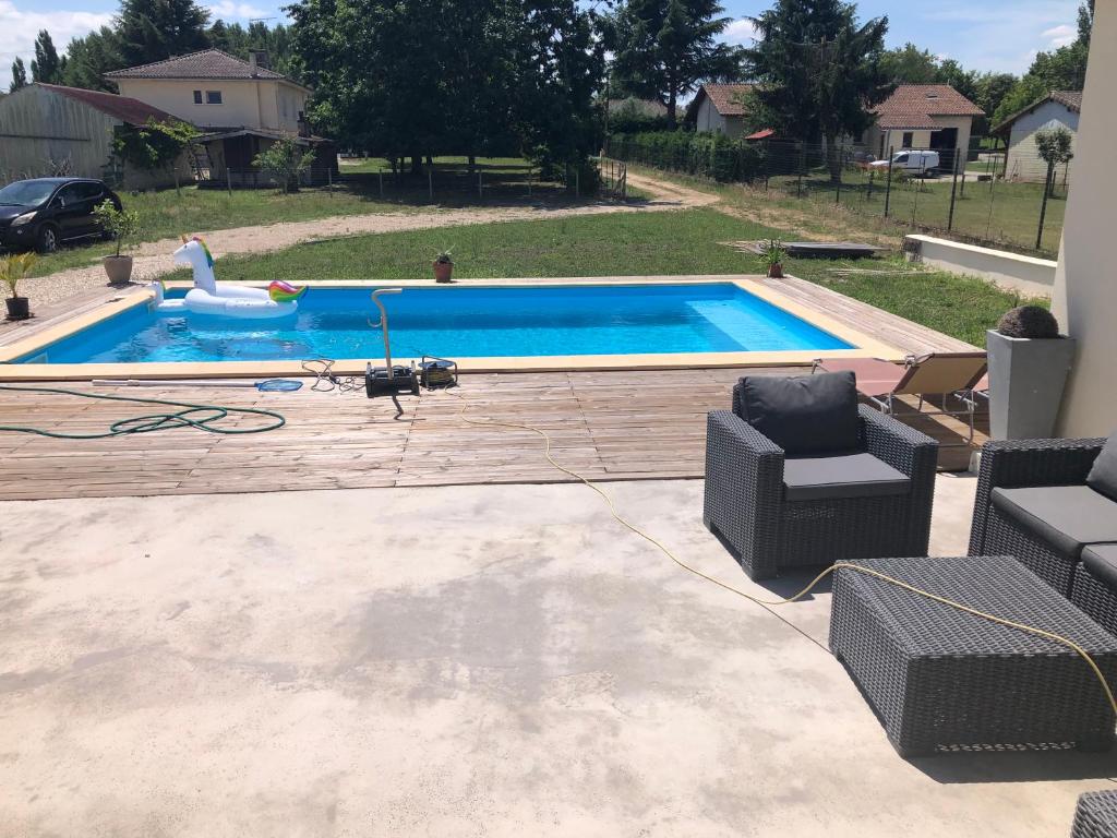 a swimming pool in a yard with two chairs next to it at Havre de paix in Fontet