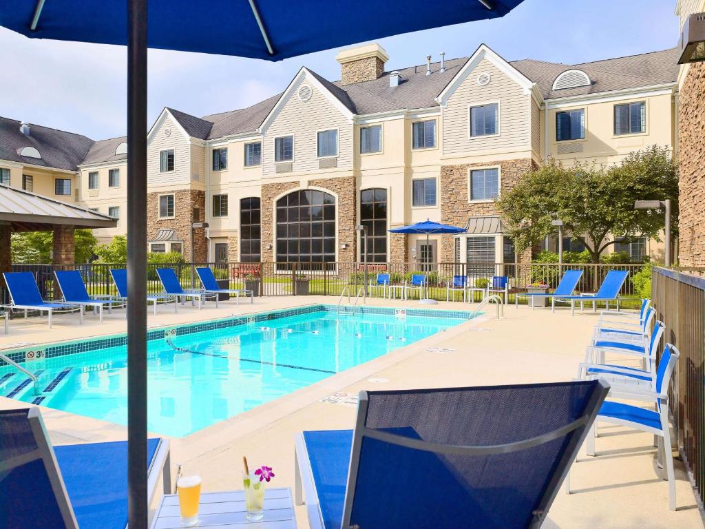 a swimming pool with blue chairs and a building at Sonesta ES Suites Houston Galleria in Houston