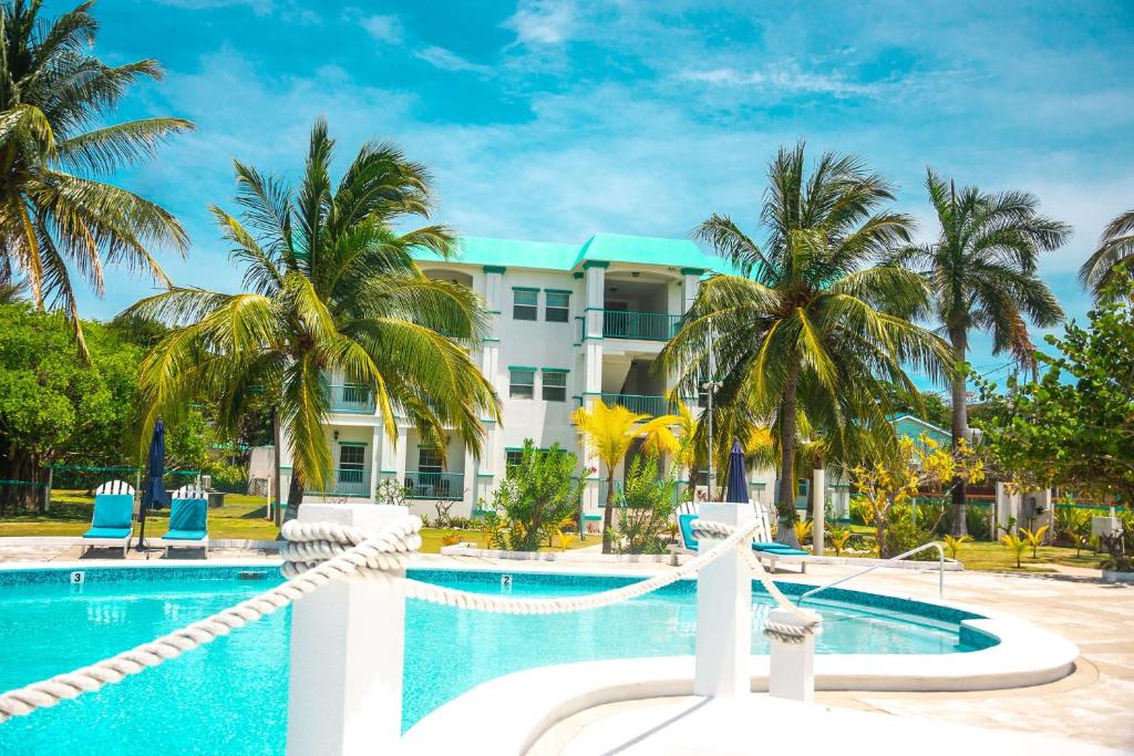 a resort with a swimming pool and palm trees at Best Western Grand Baymen Gardens in San Pedro