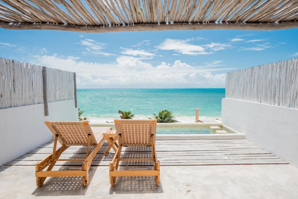 two chairs sitting on a patio with the ocean at Punta Blanca Beach House in Costa Mujeres