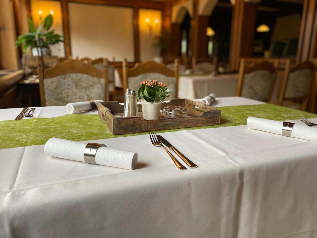 una mesa con un mantel blanco y una bandeja de madera con flores. en Hotel-Garni Domblick en Bad Honnef am Rhein