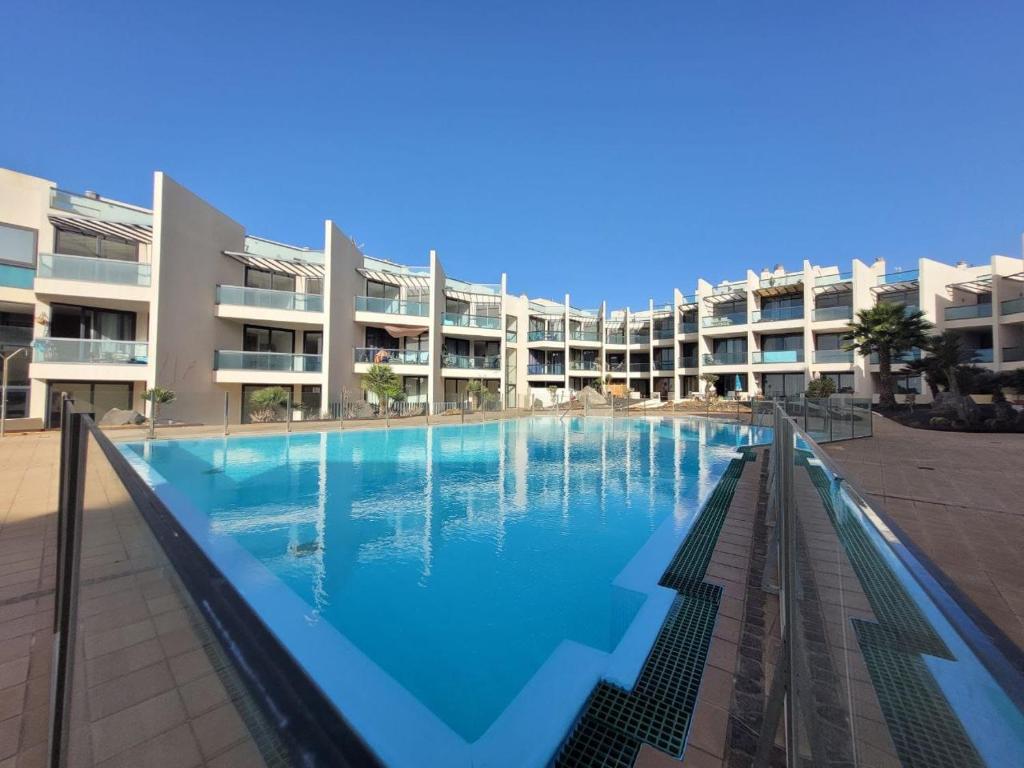 a large swimming pool in front of a building at Cozy 1 Bedroom Apartment with Sea View in Cotillo