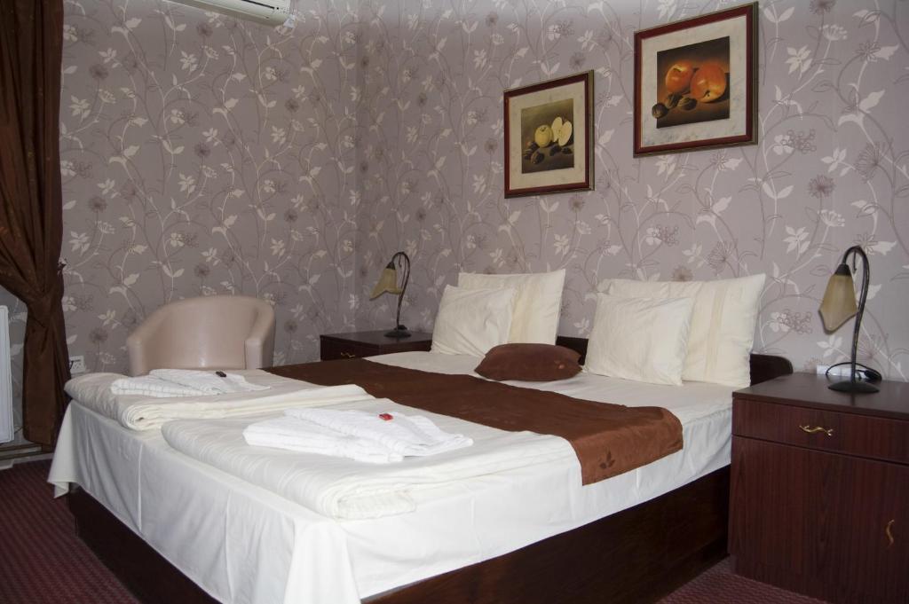 a hotel room with a large bed with white sheets at Guest House Prenoćište Piccolina in Sombor