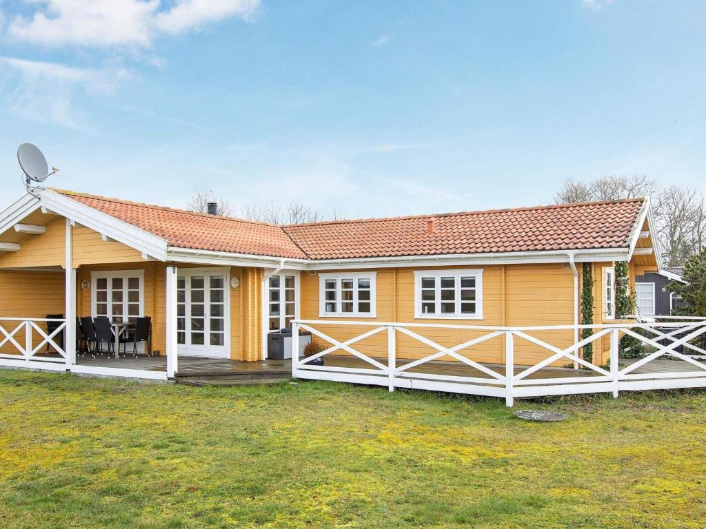 une maison jaune avec une clôture blanche devant elle dans l'établissement 6 person holiday home in Slagelse, à Slagelse