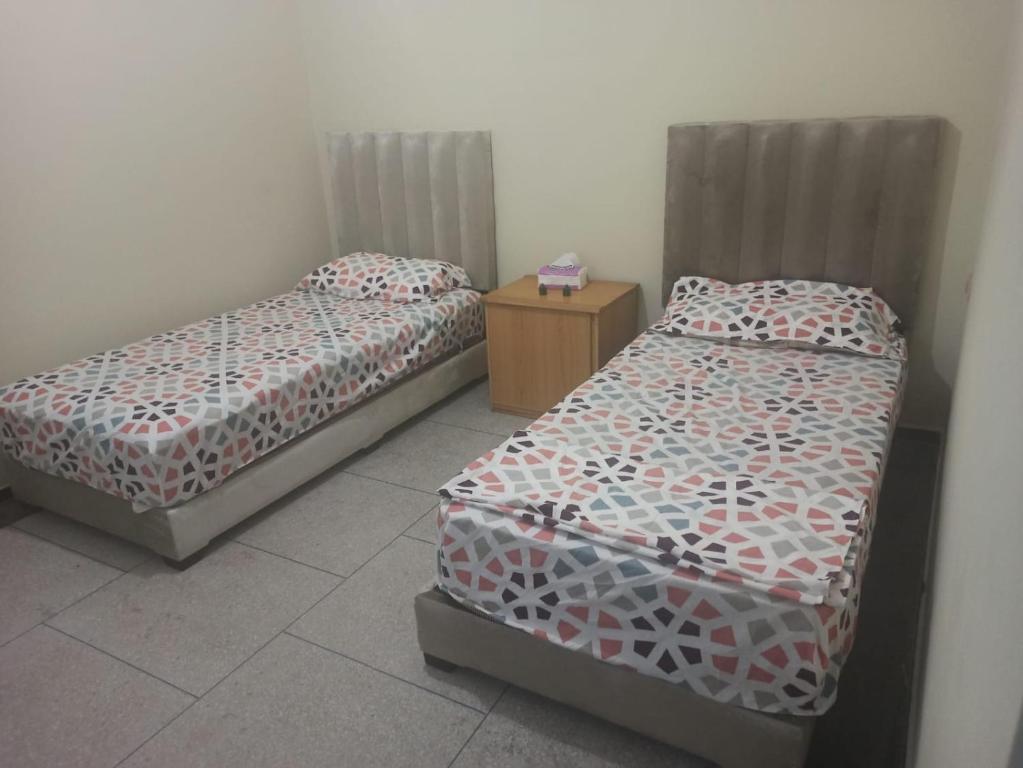 a room with two beds and a night stand at Quartier Anne Marie in Temara
