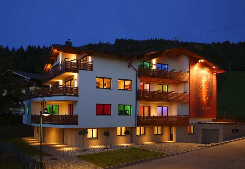 a building with illuminated windows and balconies at night at Aparthotel Rubinius in Wagrain