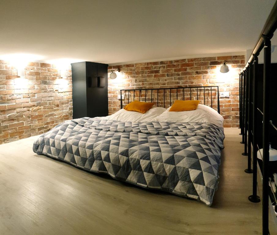 duże łóżko w pokoju z ceglaną ścianą w obiekcie Lividus Czarna Mewa w Świnoujściu
