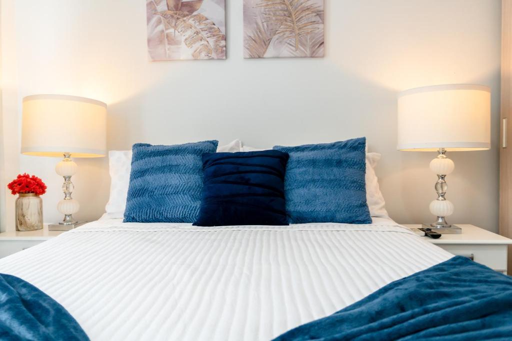 a bedroom with a white bed with blue pillows at Moderno y acogedor condominio en zona exclusiva in San Pedro Sula