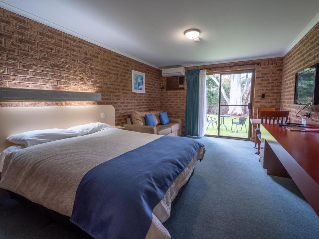 a bedroom with a bed and a brick wall at Eildon Parkview Motor Inn Room 9 in Eildon