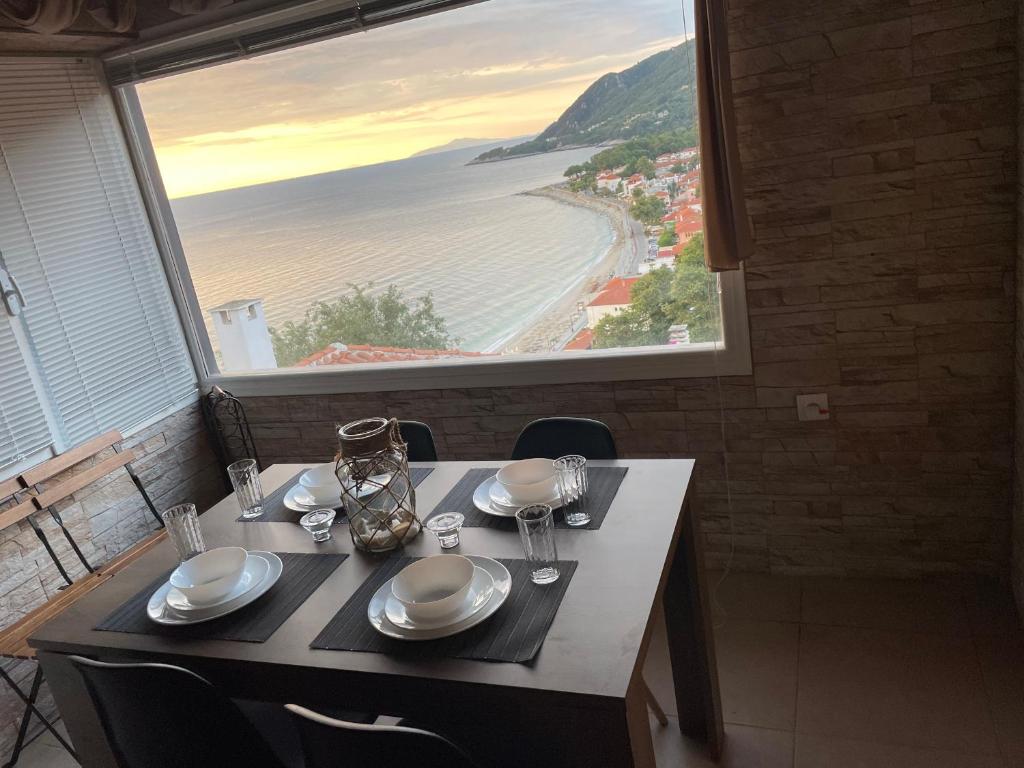 a table with a view of the ocean from a window at The Odyssey Holiday Home - Agios Ioannis, Pelion in Agios Ioannis Pelio