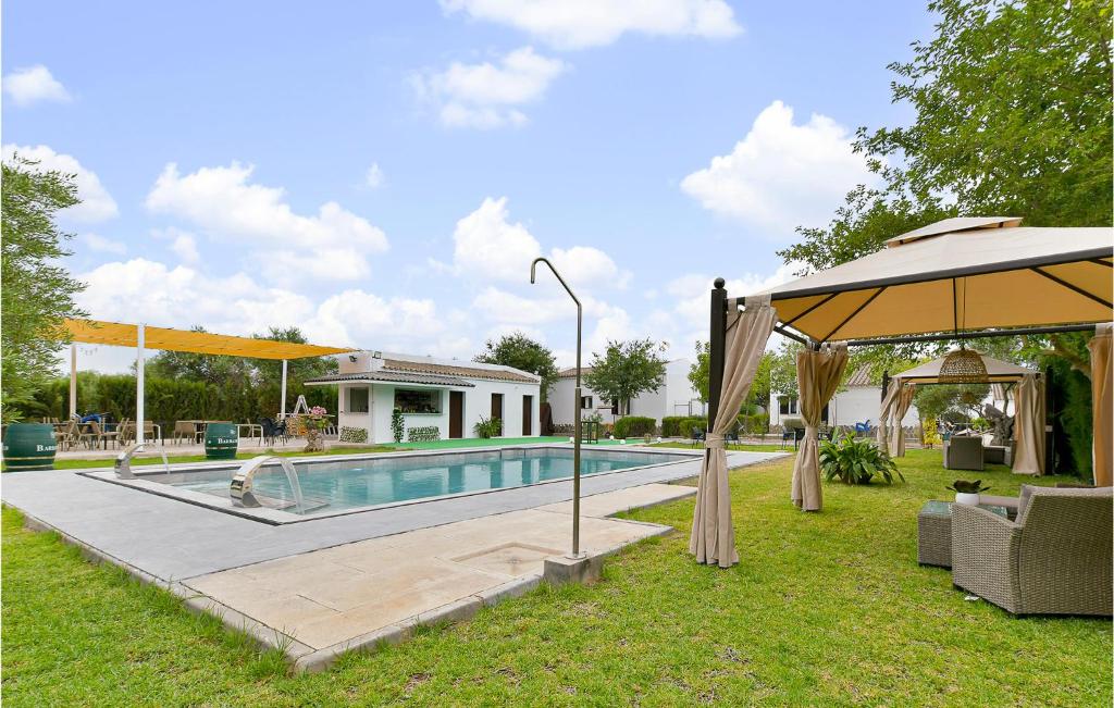 una piscina en un patio con sombrilla en Nice Home In El Coronil With Kitchenette, en El Coronil