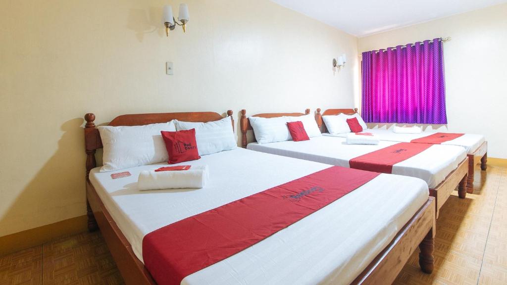 two beds in a room with red and white at RedDoorz @ Golden Victory Hotel Mabalacat Pampanga in Mabalacat