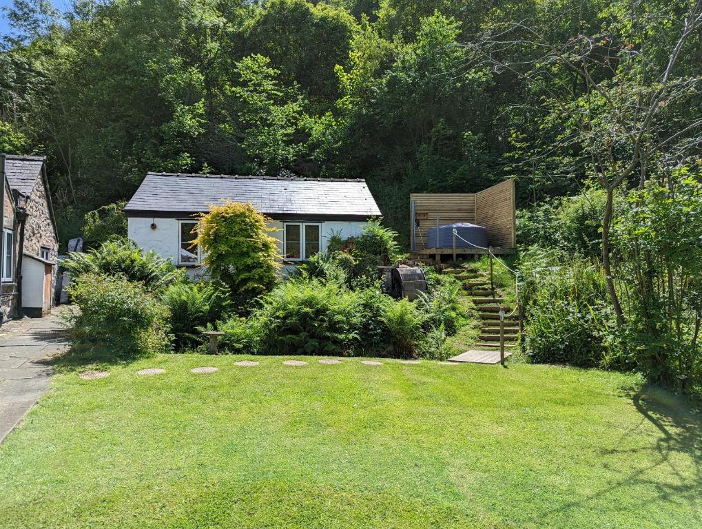 un jardín con una pequeña casa en el fondo en Little Pandy Cottage en Mold