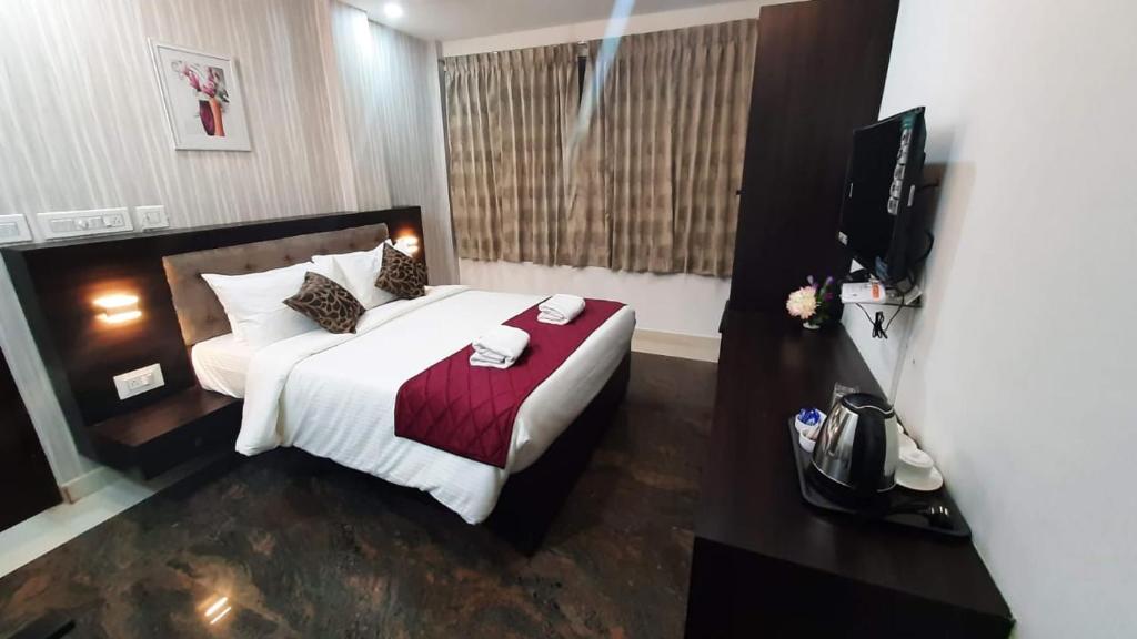 een slaapkamer met een groot bed en een televisie bij Nagas Inn by Unicorn in Krishnagiri