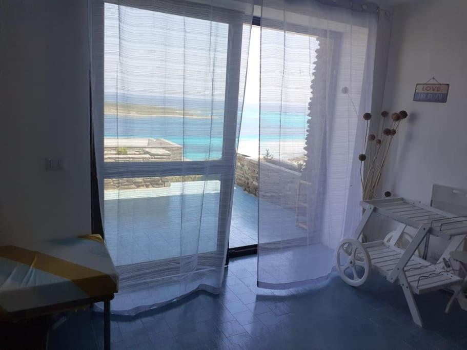 a room with a large window with a view of the ocean at Casa Capo Falcone - Terraced house with wonderful sea view - in Stintino
