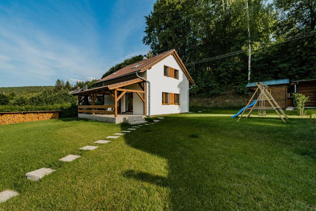 une petite maison dans une cour avec une aire de jeux dans l'établissement Na Želivce chalupa Gabriela, à Želiv